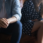 Two people sitting apart on a couch, not touching