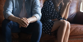 Two people sitting apart on a couch, not touching