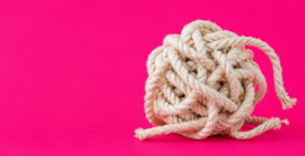 A loosely knotted ball of thick white rope sits on the right side of a vivid hot pink background, with several frayed strands beginning to unravel. The large area of empty space on the left creates a minimalist composition, suggesting the slow process of untangling a complicated relationship.