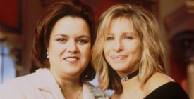 Rosie O'Donnell and Barbra Streisand smiling together at an event in November 1997, both in evening wear, standing close with arms around each other.